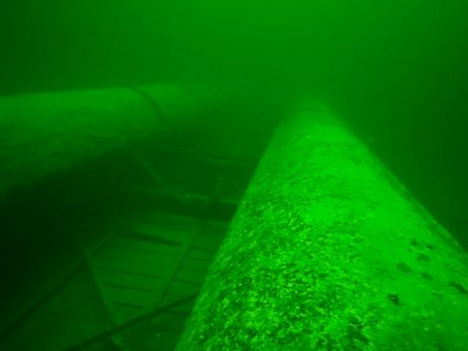 Unterwasseransicht von großen, grünen Rohren in trübem Wasser.