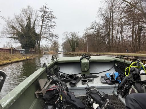 Blick von einem Boot auf einen ruhigen Kanal mit Bäumen am Ufer.